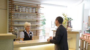 Un mostrador de recepción con encimera de madera y estantes superiores con copas y botellas.