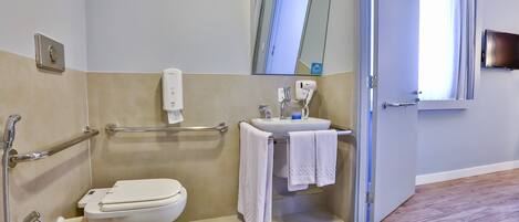 Un baño con inodoro, secamanos, lavamanos y espejo.