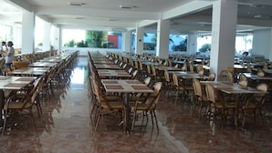 A spacious indoor dining area with rows of tables and chairs, large windows, and a view of palm trees outside. - Reserva Caldas Lacqua 4 (Caldas Novas)