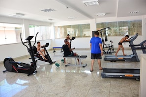 Ein Fitnessstudio mit Laufbändern, Crosstrainern und Hantelbänken.