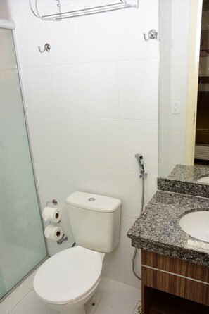 A bathroom with a toilet, a shower, and a sink with a granite countertop. - Reserva Caldas Lacqua 4 (Caldas Novas)