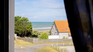 Vista costera con una casa, árboles y una playa.