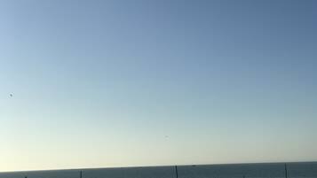 A coastal view with a clear sky, a sandy beach, and a calm sea.
