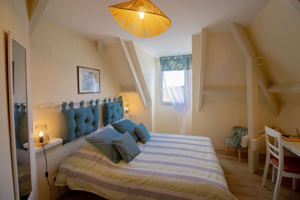 Un dormitorio con cama, lámparas de noche, un escritorio y una silla.