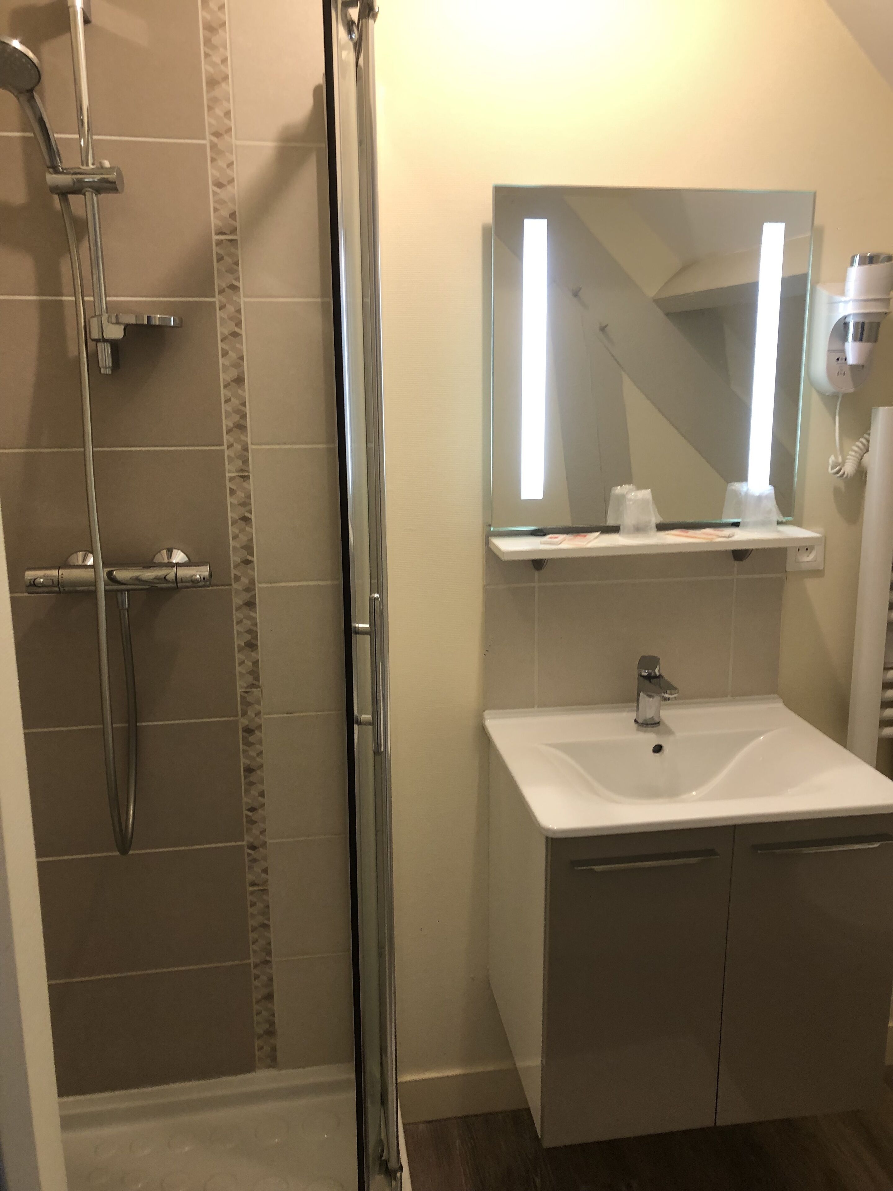 A bathroom with a shower, a sink, a mirror, and a hairdryer.