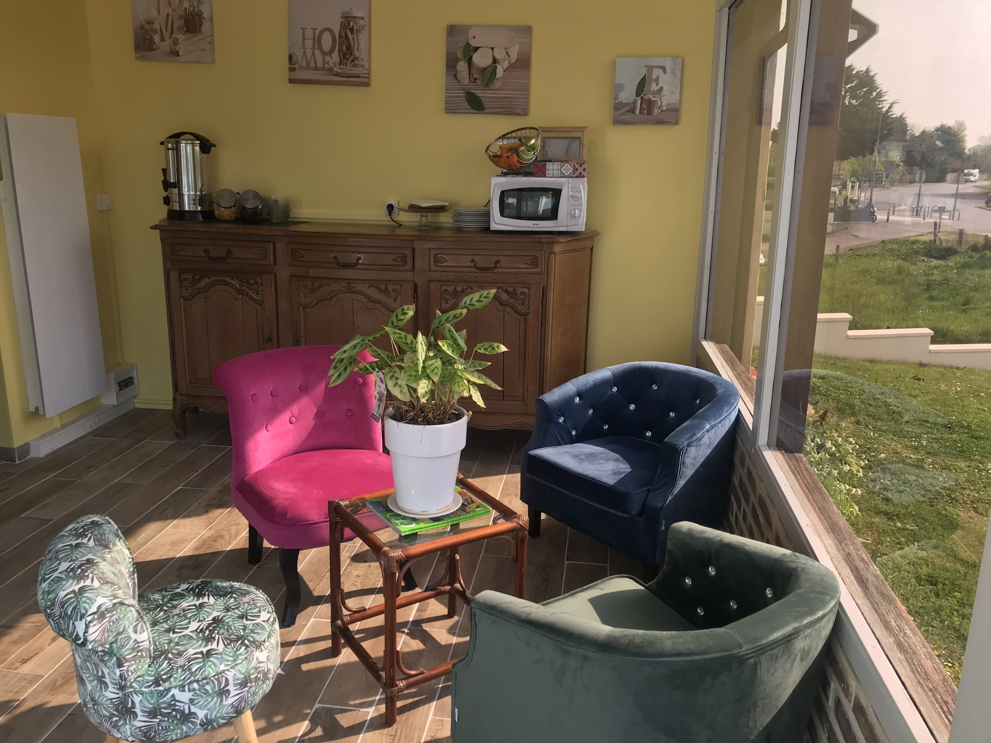 A cozy patio area with a wooden cabinet, a potted plant, and two upholstered chairs.