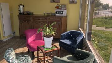 A cozy patio area with a wooden cabinet, a potted plant, and two upholstered chairs.