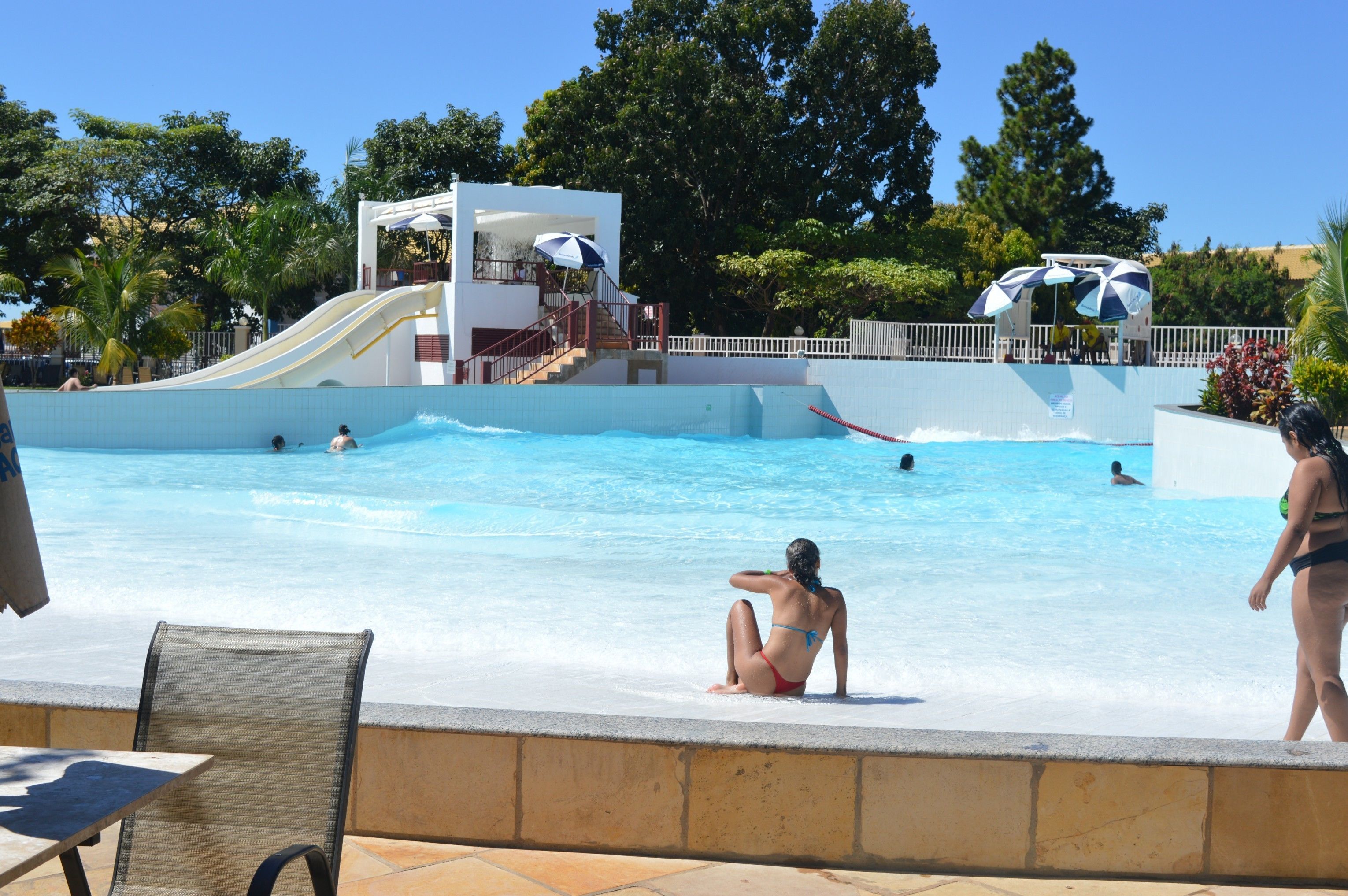 Ein Swimmingpool mit Rutsche, Liegestühlen und Sonnenschirmen.