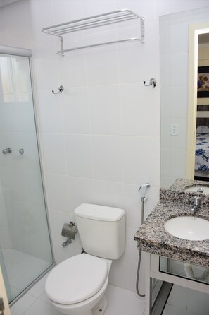 A bathroom with a glass shower enclosure, a white toilet, and a granite countertop sink. - Reserva Caldas Lacqua 5 (Caldas Novas)