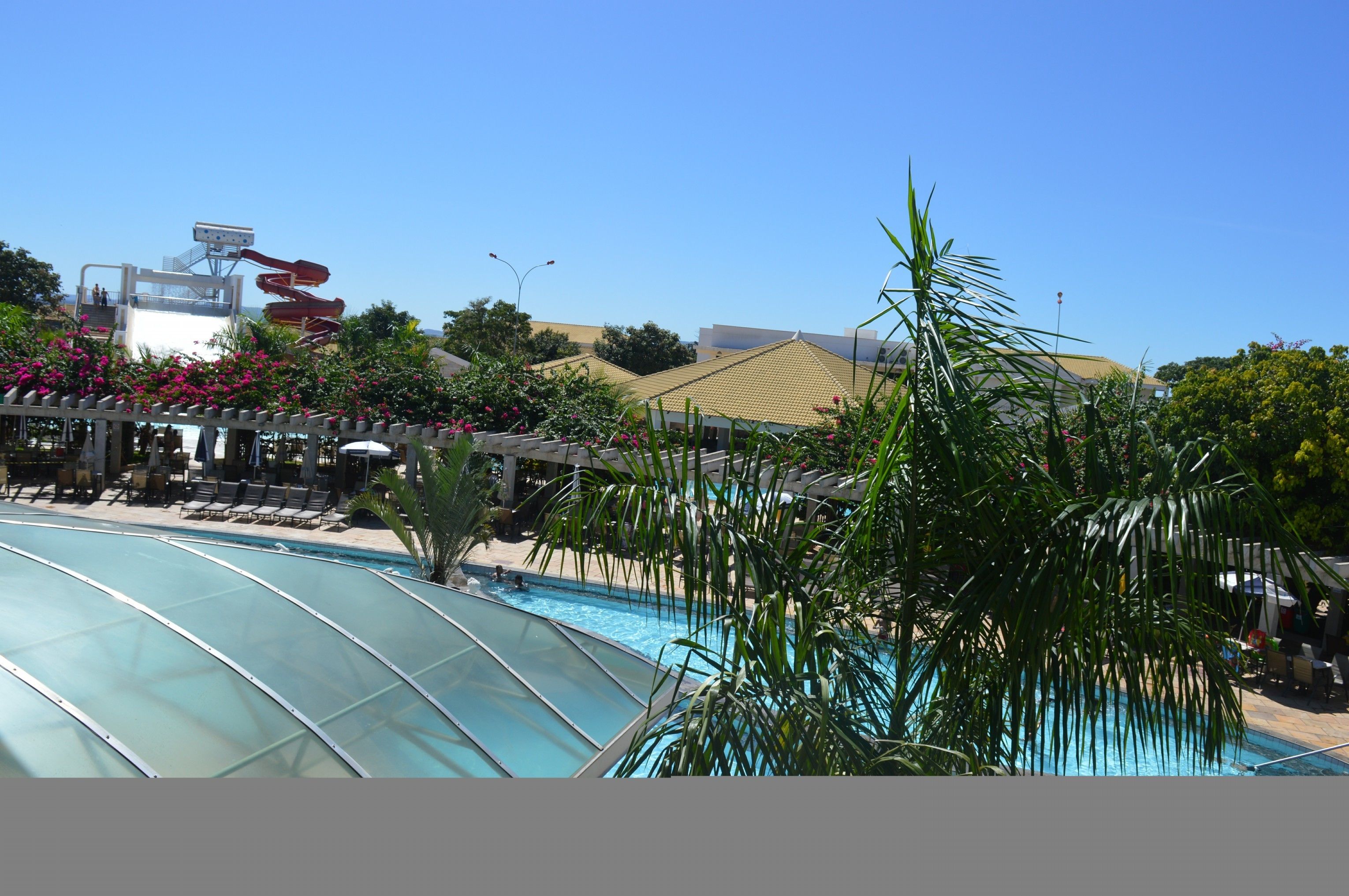A pool area with a glass roof, lounge chairs, and a water slide.