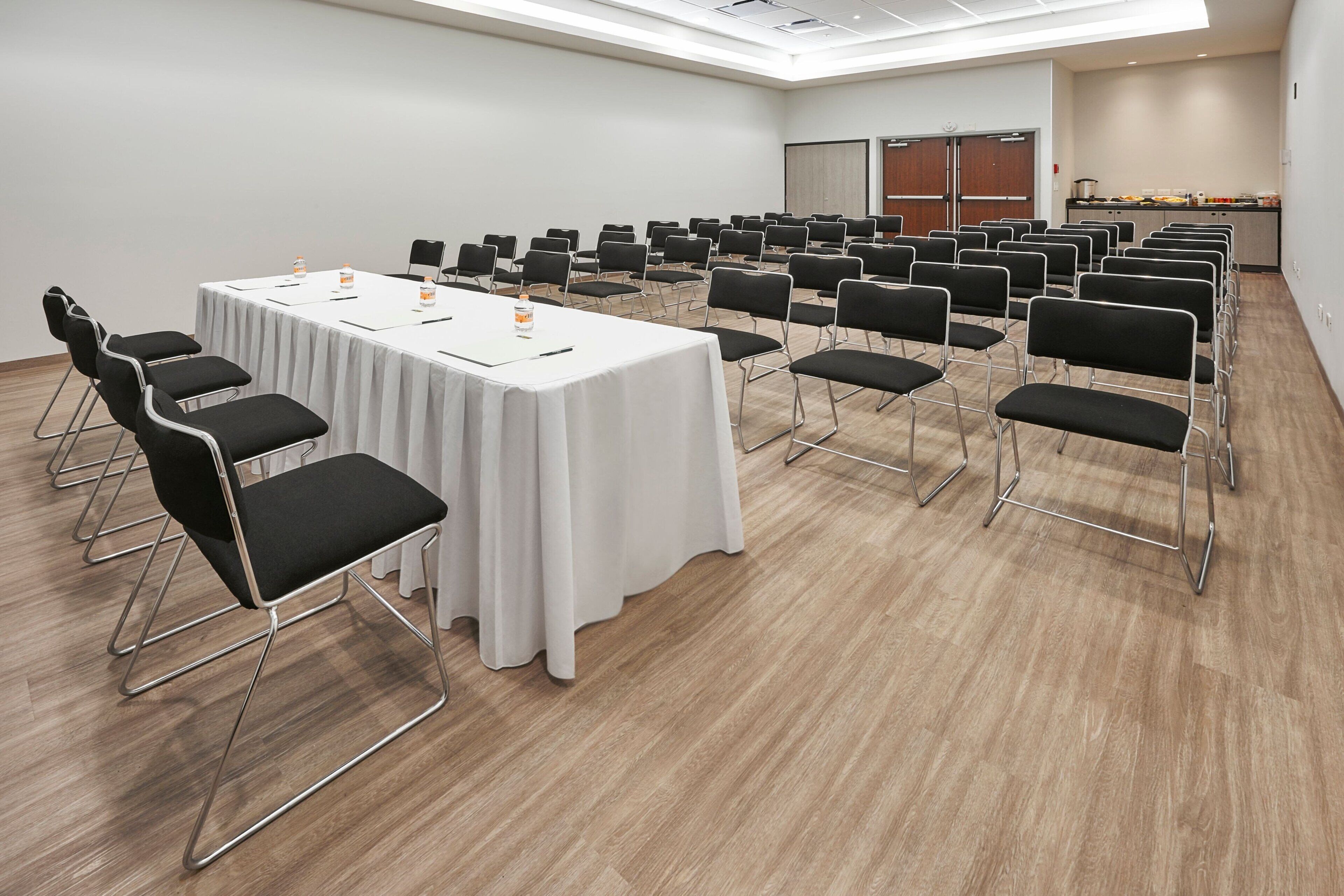 Uma sala de conferência com uma mesa comprida, várias cadeiras e uma tela de projetor.