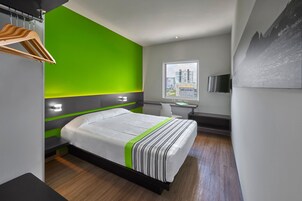 Een moderne hotelkamer met een bed, een bureau en een raam met uitzicht op de stad.