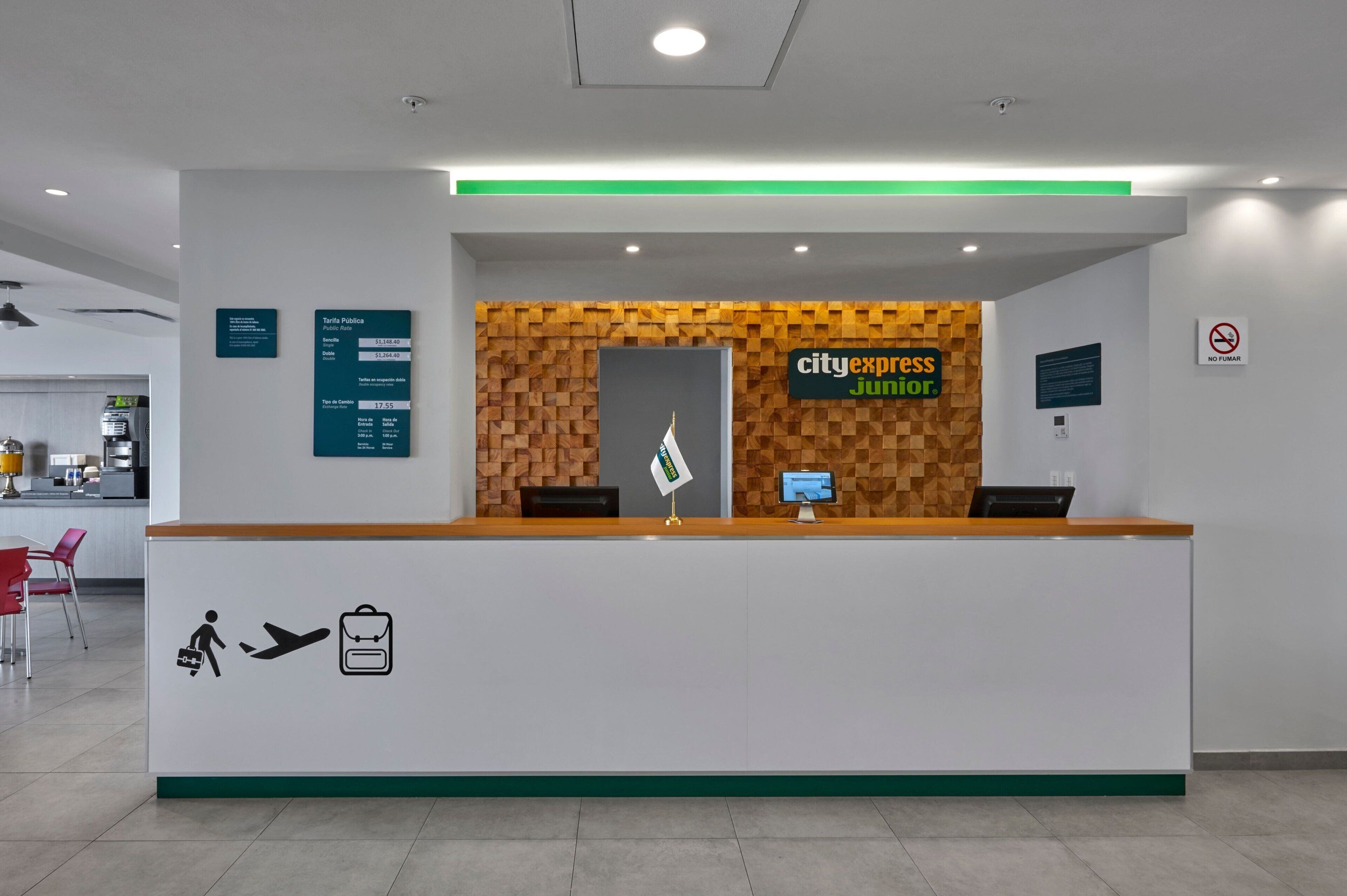 A reception desk with a 'cityexpress junior' sign, a 'Tercia Publica' sign, and a 'NO TUMAR' sign.