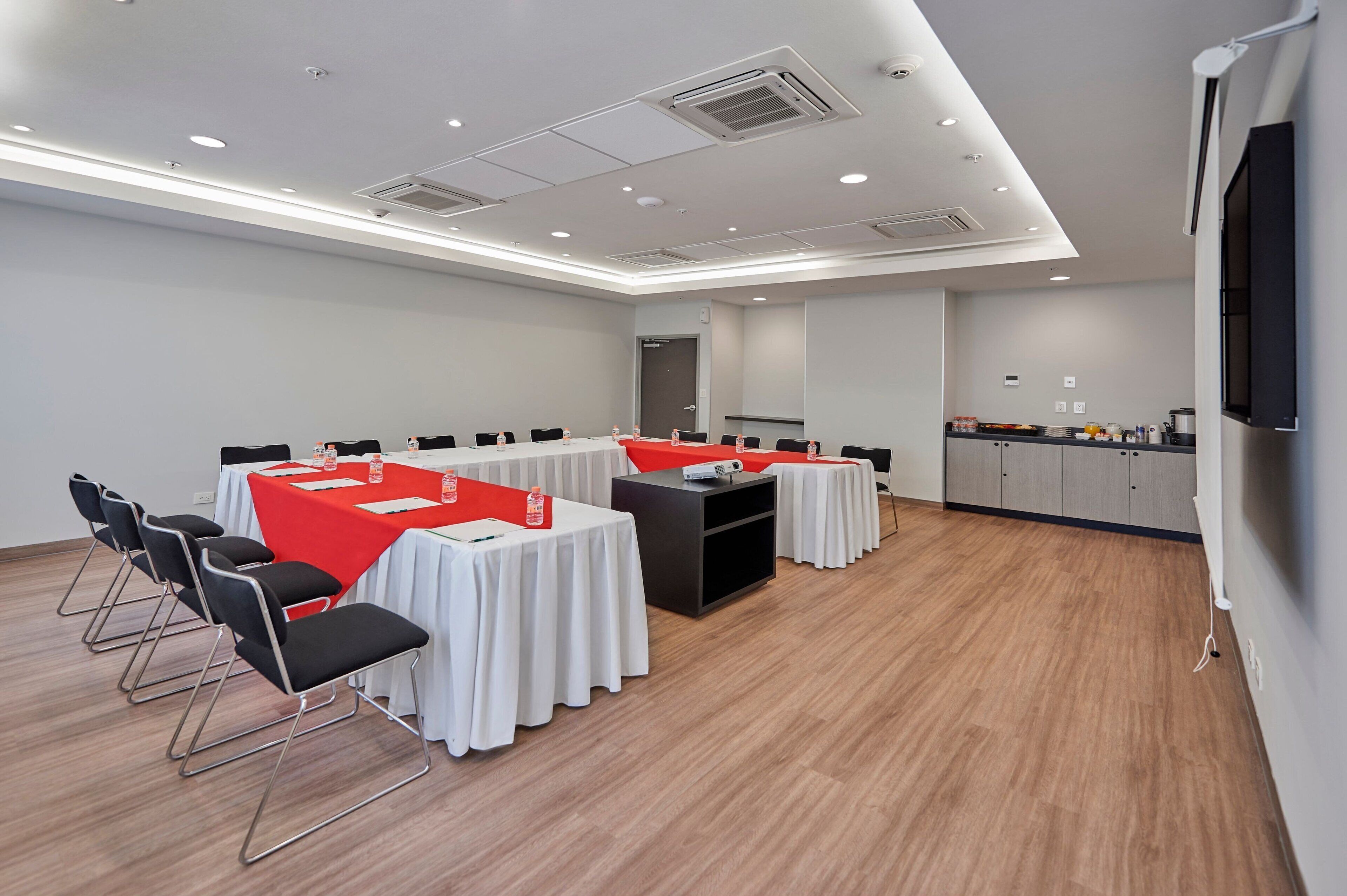 A conference room with white tables, black chairs, and a red accent table.