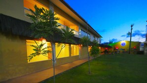 A modern building with a well-lit exterior, a visible entrance, and a small lawn area. - Pousada Recanto dos Corais (Ipojuca)