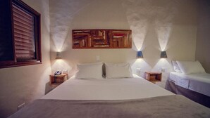 Een hotelkamer met een groot bed, twee nachtkastjes, een kunstwerk aan de muur en twee wandlampen.