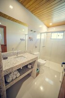 Un baño moderno con lavamanos de granito, inodoro blanco y ducha con cerramiento de vidrio.