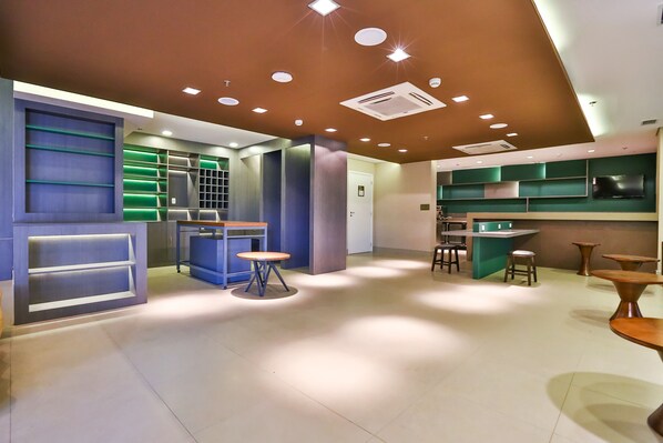 A modern interior with a reception desk, seating area, and kitchen space. - Hilton Garden Inn Santo André (Santo André)