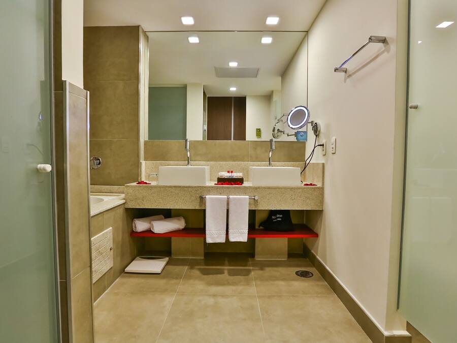 A modern bathroom with two sinks, a mirror with a built-in light, and a shower area.