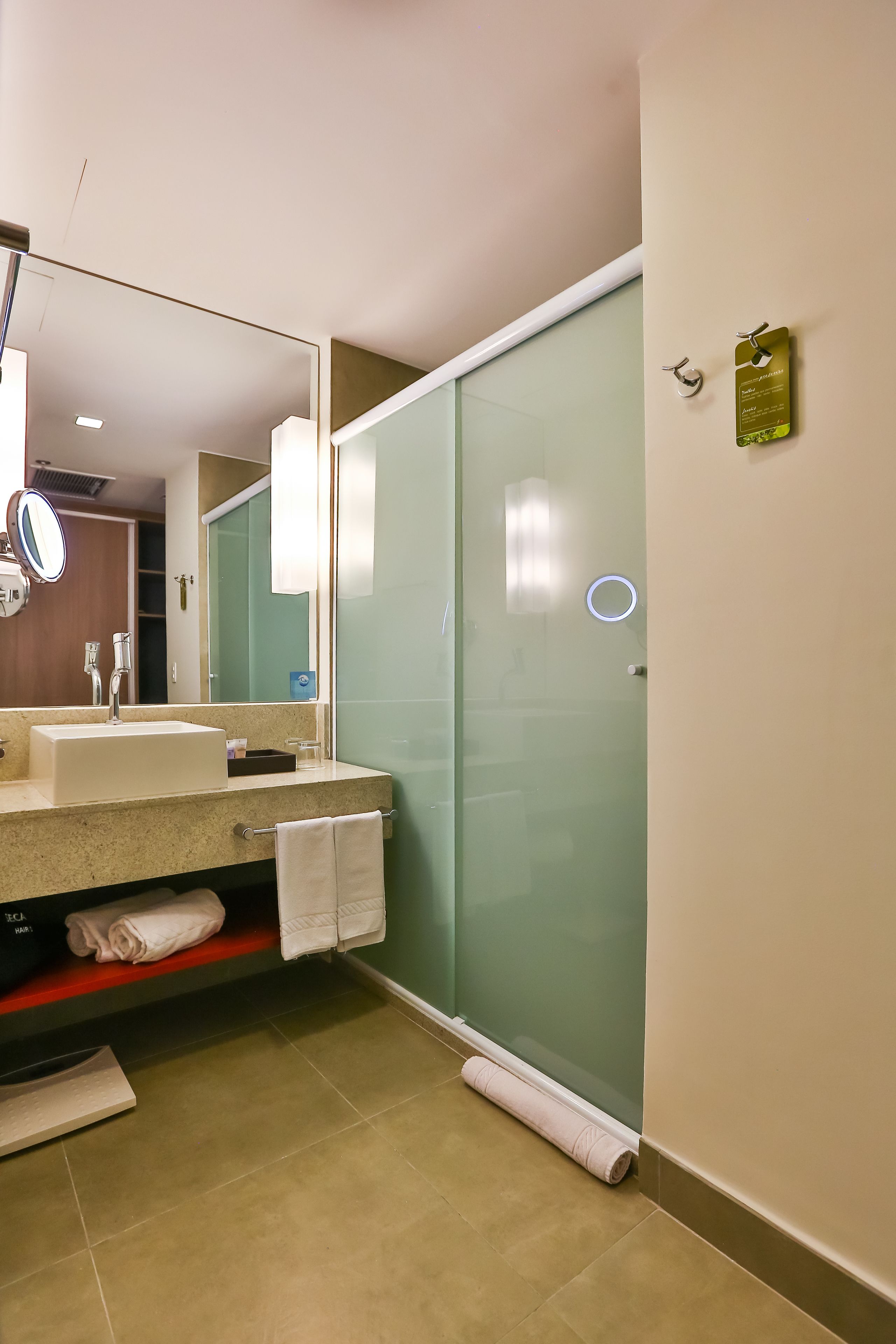 Een moderne badkamer met een wastafel, spiegel en een douchecabine met glazen wanden.