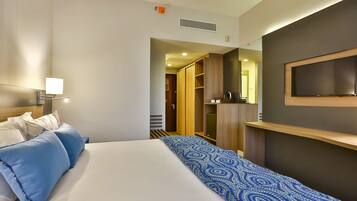 Una habitación de hotel con cama, televisor montado en la pared y armario.