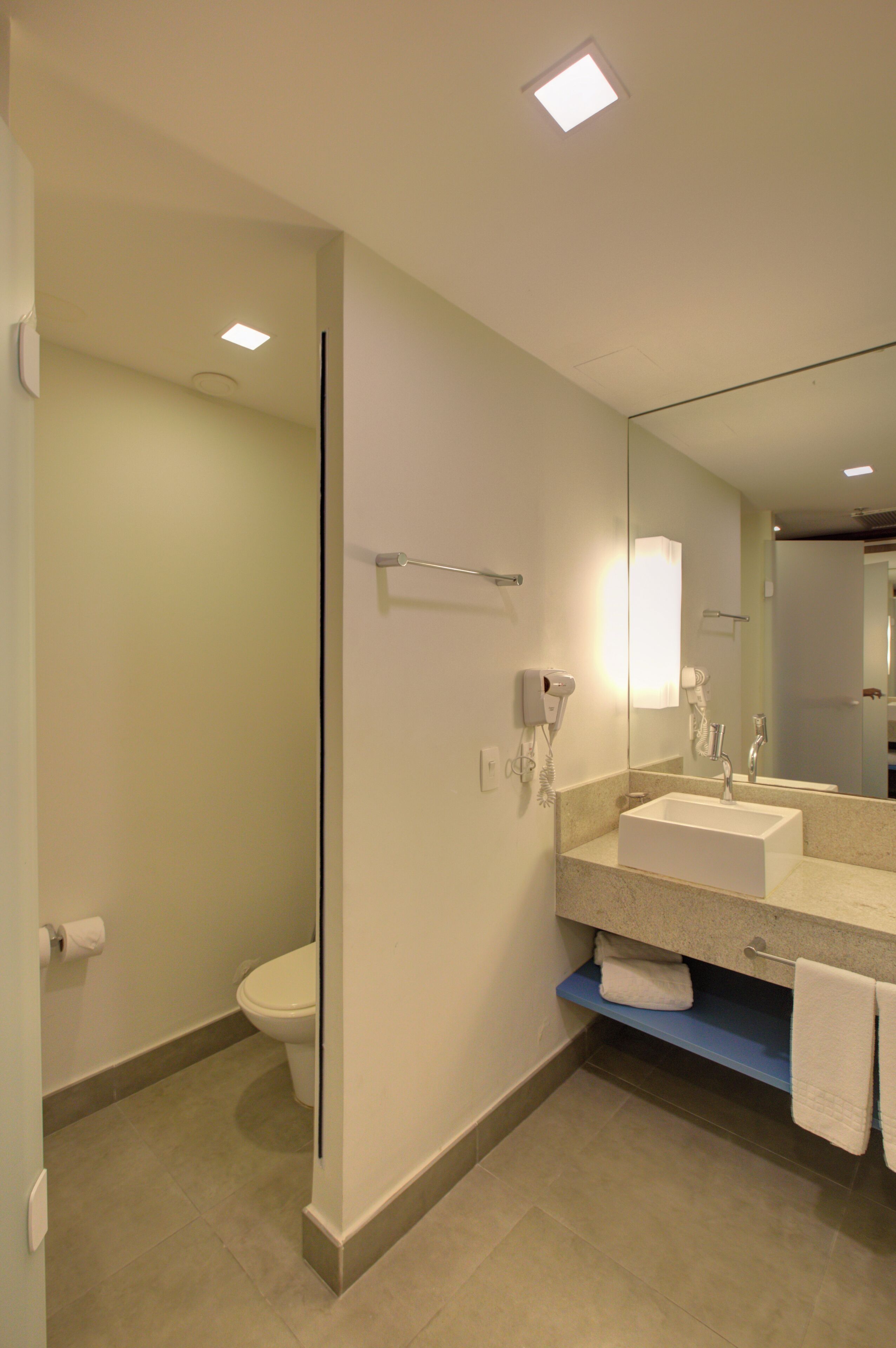 A modern bathroom with a white sink, a mirror, and a toilet.