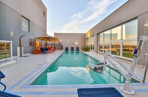 A rooftop pool with clear blue water, a lifeguard stand, and a seating area with umbrellas. - Hilton Garden Inn Santo André (Santo André)