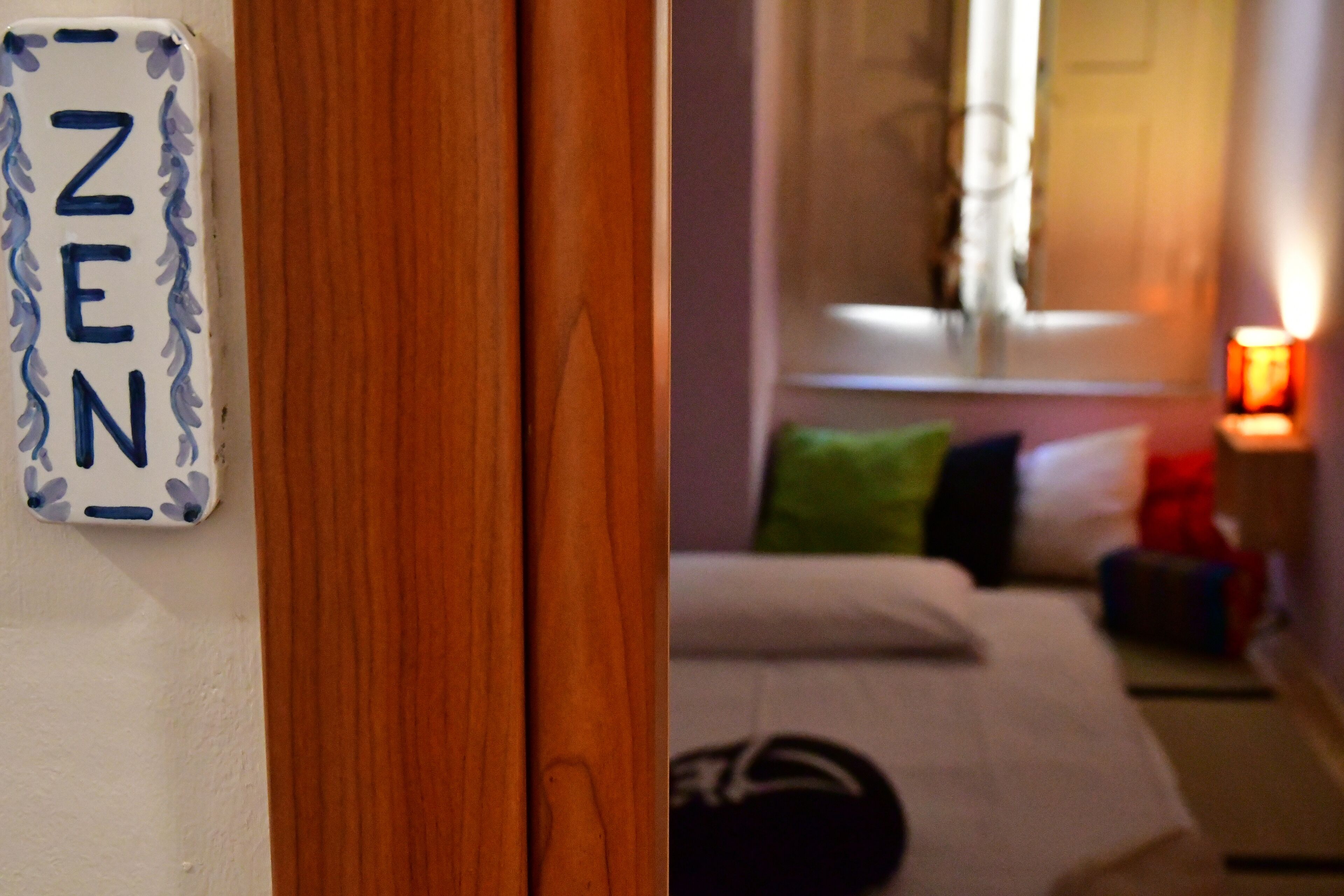 Una habitación con una cama, almohadas, una mesita de noche con lámpara y un cartel en la pared con la palabra 