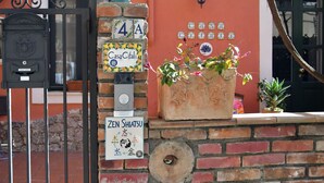 Un buzón, una planta en maceta y un letrero de Zen Shitsu en una pared de ladrillo.