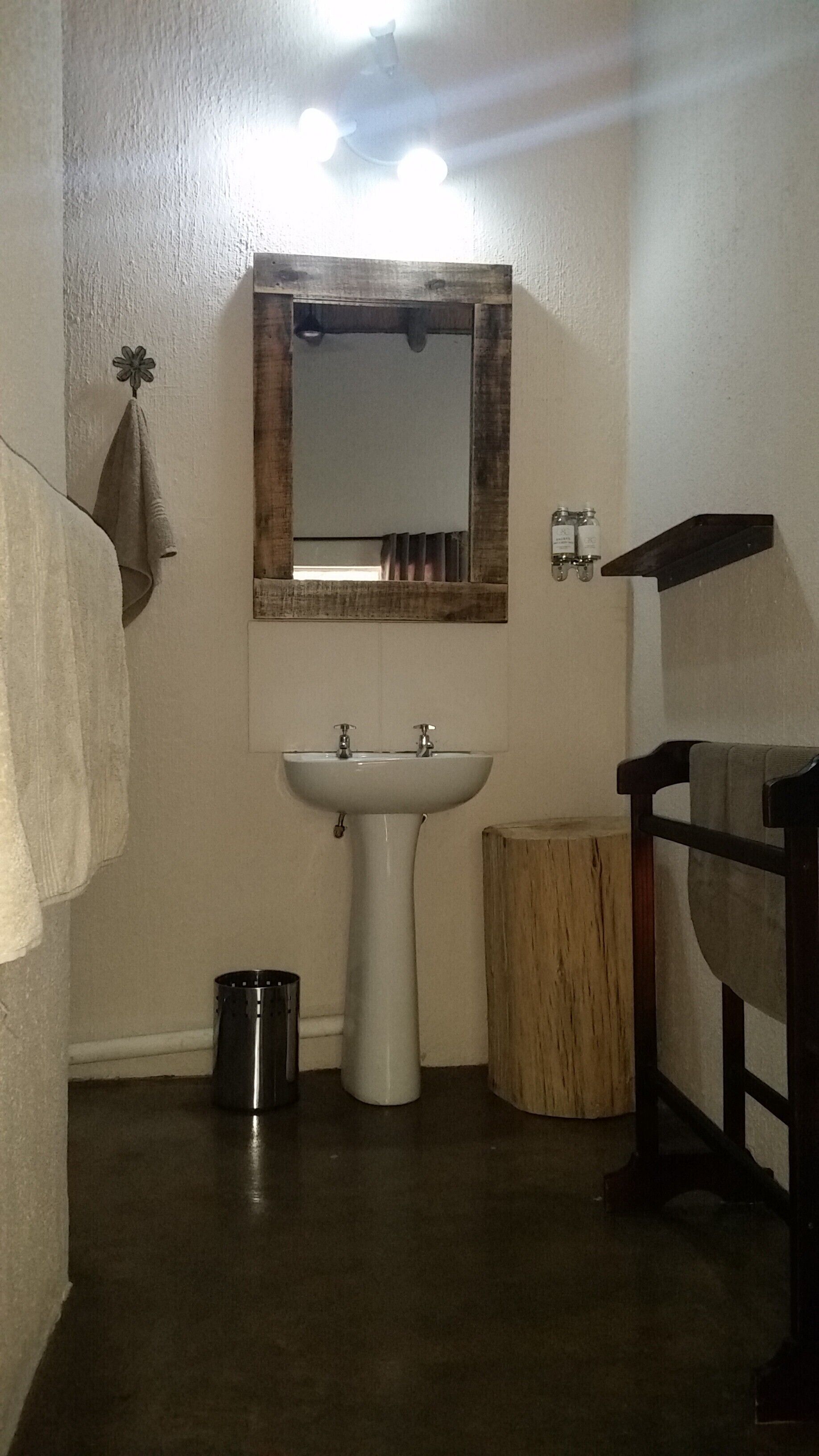 Une salle de bain avec un lavabo blanc, un meuble-lavabo en bois, un miroir avec un cadre en bois et une serviette accrochée au mur.