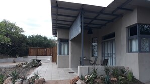 Una casa moderna con un porche cubierto, cerca de madera y diversas plantas.