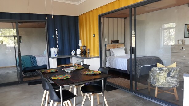 Una habitación moderna con una mesa de comedor, dos camas y una zona de cocina.