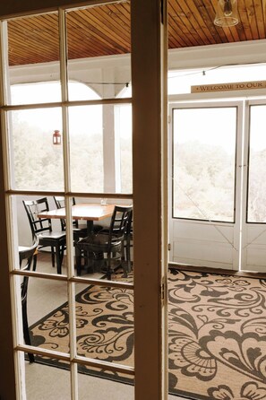 Step into a cozy space with a dining table and comfortable seating, surrounded by a large window and a stylish rug.