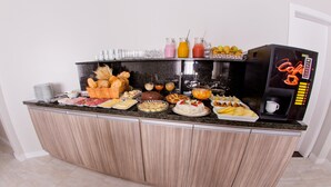 A breakfast buffet with various food items and a coffee machine. - North Hotel (Chapecó)