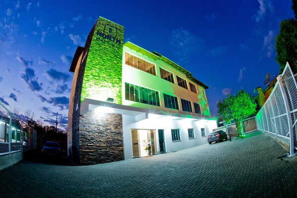 A modern hotel with a stone facade, multiple windows, and a paved driveway. - North Hotel (Chapecó)