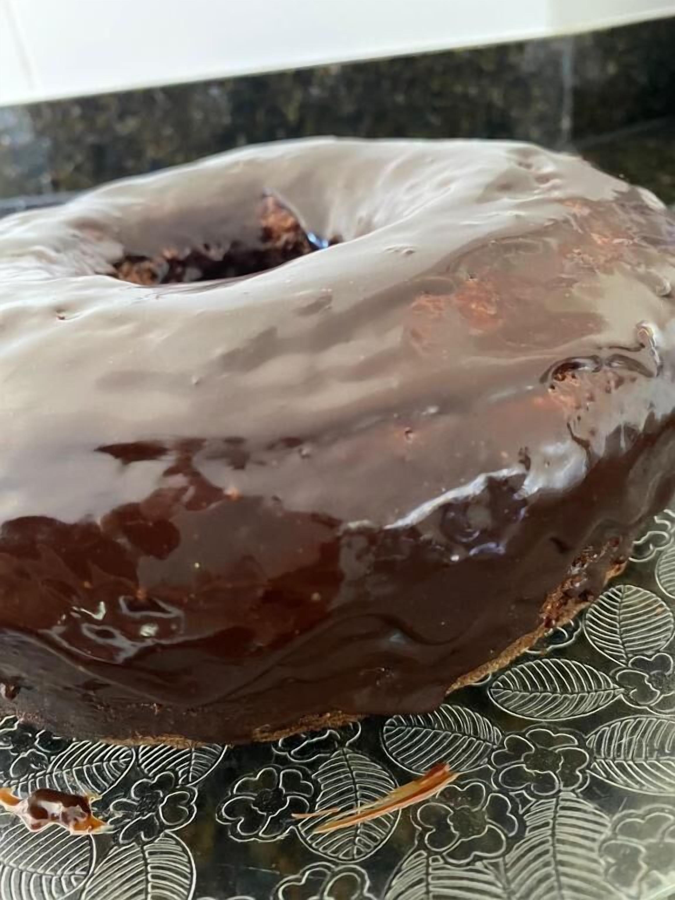 Un donut cubierto de glaseado de chocolate sobre un plato estampado.