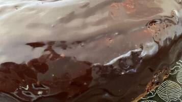 Un donut cubierto de glaseado de chocolate sobre un plato estampado.