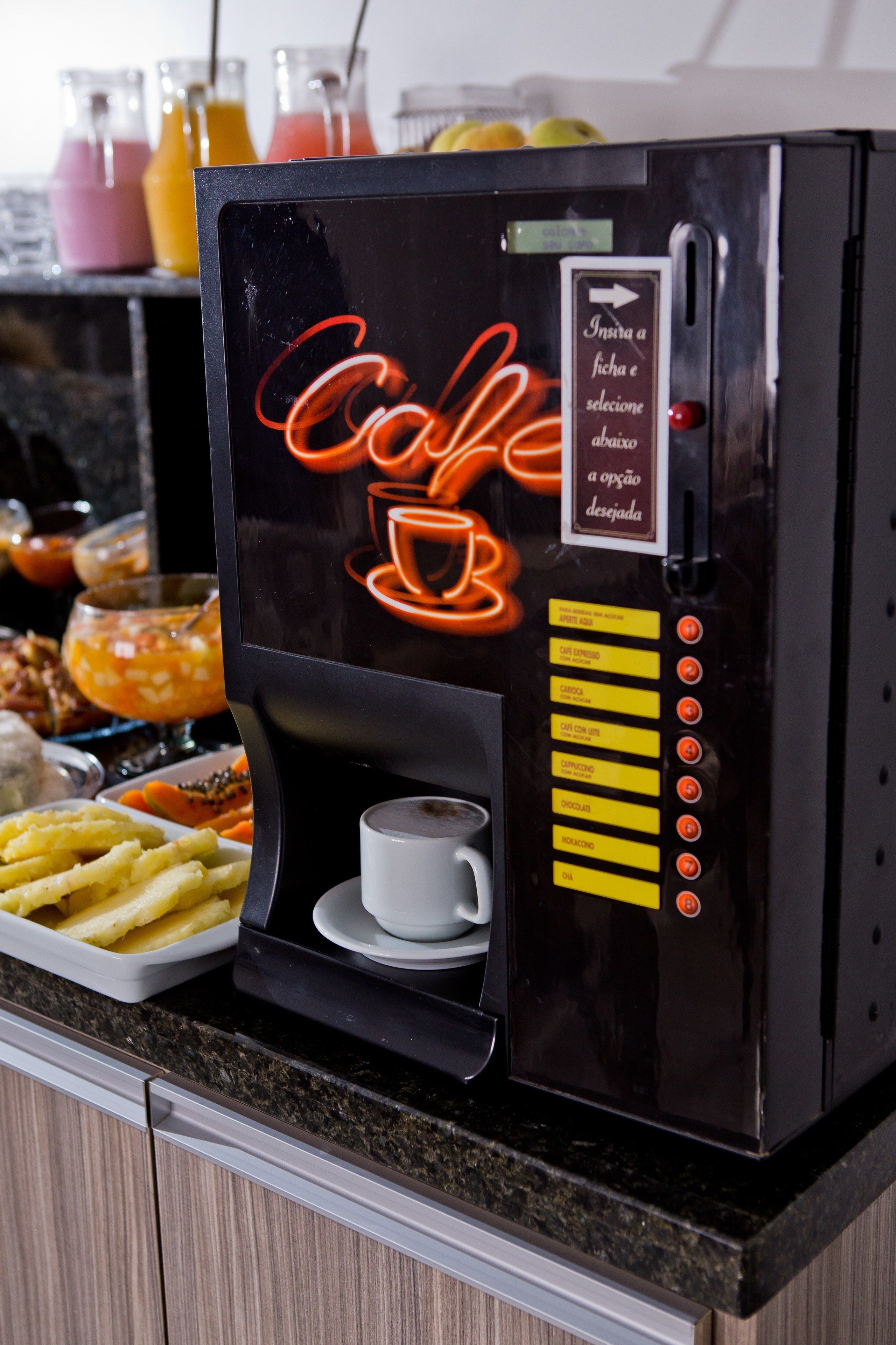 Eine Kaffeemaschine mit einer Neonreklame, einer Tasse und einer Portion Pommes.