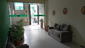A reception area with a sofa, a staircase, and potted plants. - Cachoeira Apart Hotel (Cachoeira)