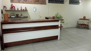 A reception desk with a wooden finish, a wall-mounted artwork, and a metal security gate. - Cachoeira Apart Hotel (Cachoeira)