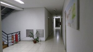 A hallway with a fire extinguisher, a potted plant, and a staircase. - Cachoeira Apart Hotel (Cachoeira)