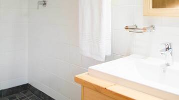 A modern bathroom with a shower, a sink, and a mirror.