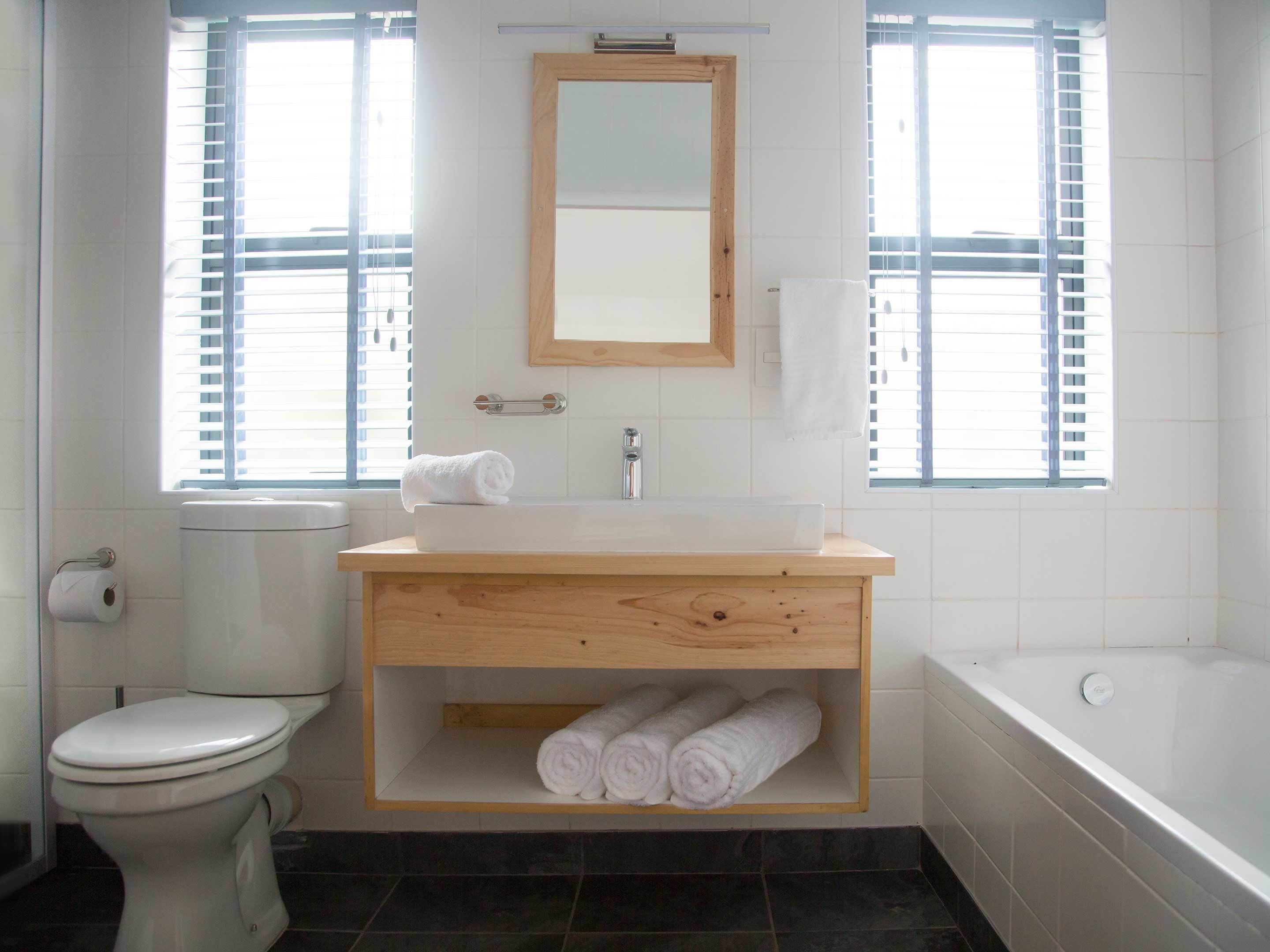 A bathroom with a toilet, sink, mirror, and bathtub.