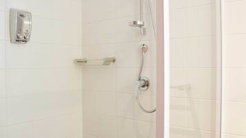 A shower with a handheld showerhead, a wall-mounted soap dispenser, and a towel rack.