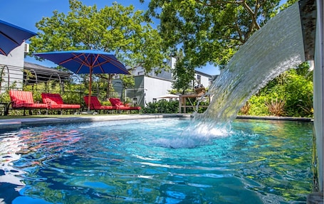 Una piscina al aire libre, sillones reclinables de piscina