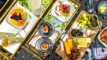 A table with various food items, including fruits, cheese, and bread, arranged on a tray.