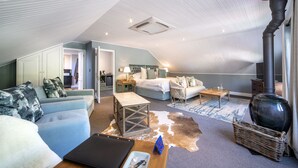 A cozy, well-lit room with a bed, a sofa, a small table, and a fireplace. - La Fontaine (Franschhoek)