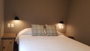 Ein Schlafzimmer mit einem Bett, zwei Nachttischlampen und einem hölzernen Kopfteil.