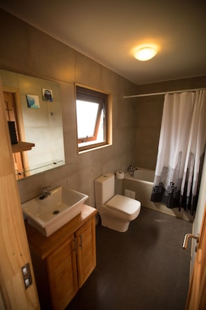 A bathroom with a sink, toilet, bathtub, and a window with a view.