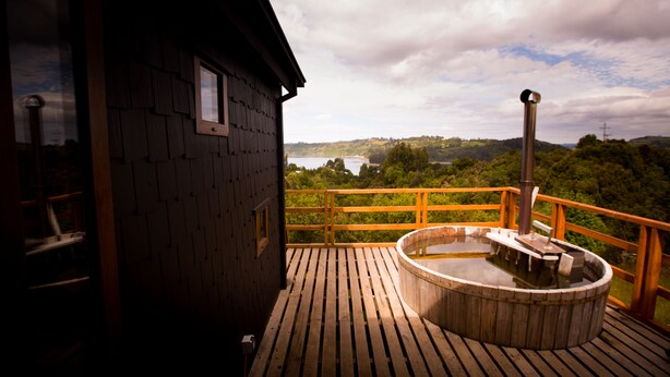 Eine Holzterrasse mit Whirlpool und eine Holzhütte mit Fenster.